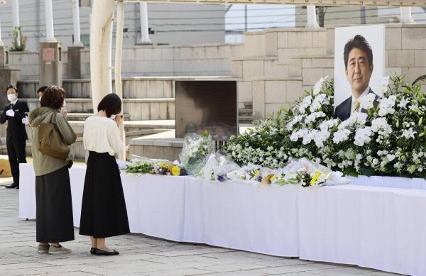 People pray at a flower stand near the venue of the prefectural-spo<em></em>nsored funeral for slain former Prime Minister Shinzo Abe in Shimonoseki, Yamaguchi Prefecture, which was his constituency, on Oct. 15. | KYODO
