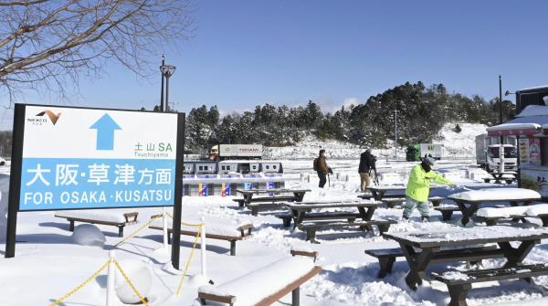 Workers remove snow at a service station on the Shin-Meishin Expressway in Shiga Prefecture on Thursday. | KYODO
