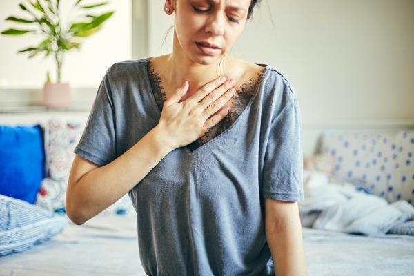 Woman havin<em></em>g a pain in the heart area while sitting at home.heart disease